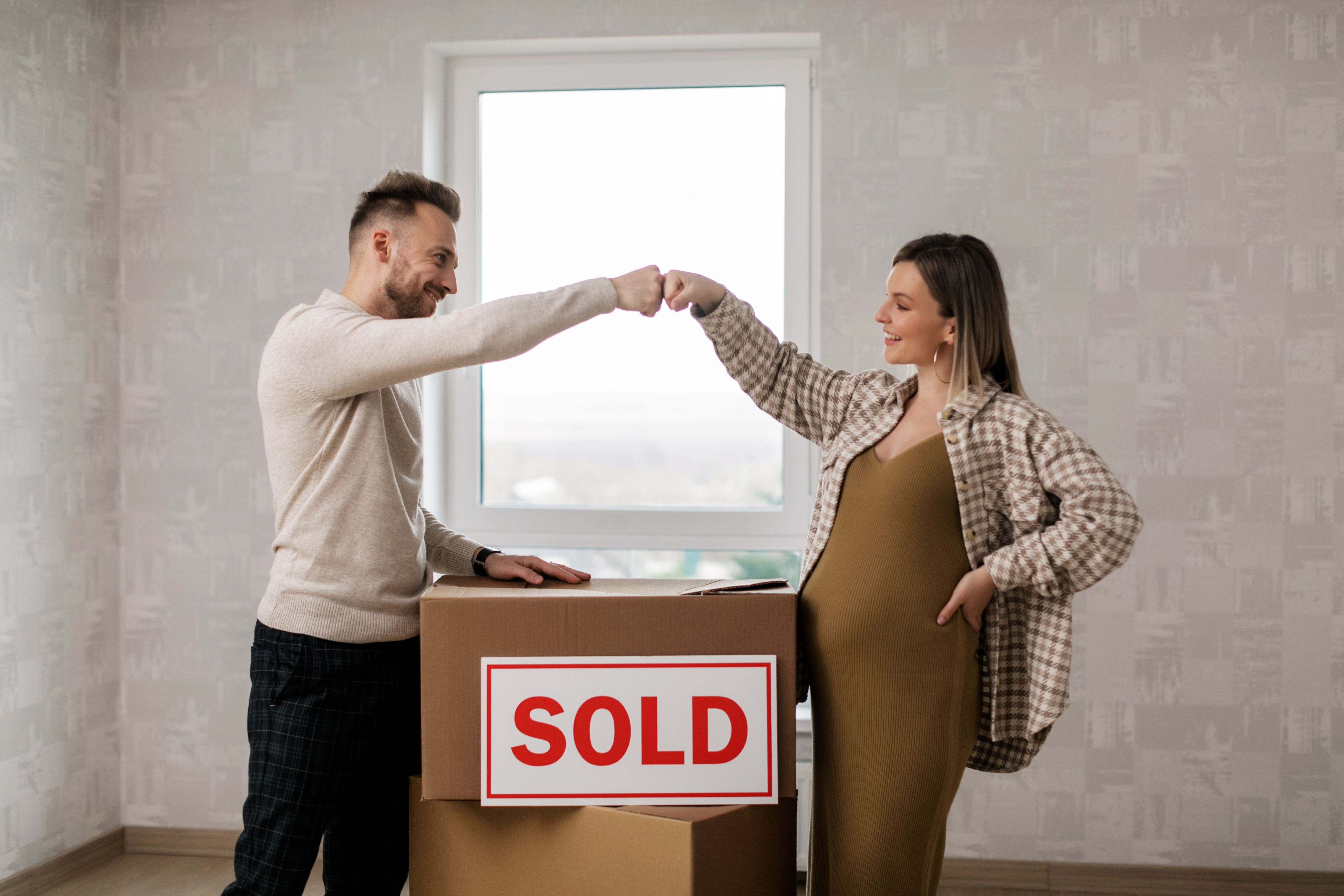 Young couple standing in front of a new home while reviewing FHSA, TFSA, and RRSP savings options