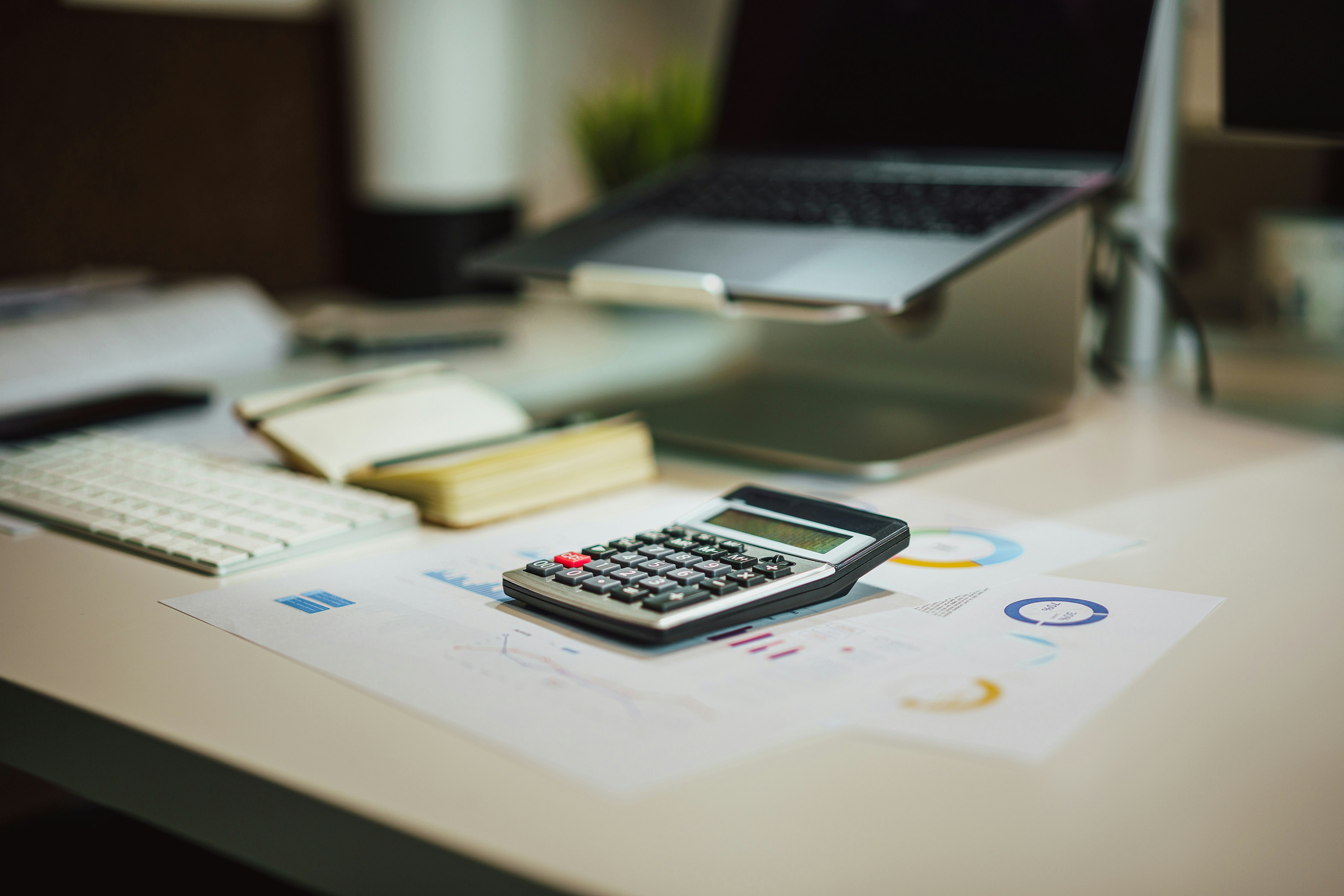 Laptop, calculator, notebook, and coffee used for a savings and investment review